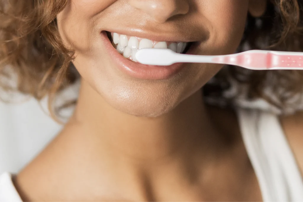 Patiente souriante tenant une brosse à dents après ses soins