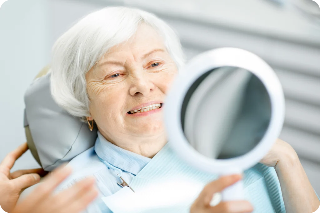 Patiente âgée souriante se regardant dans un miroir de poche